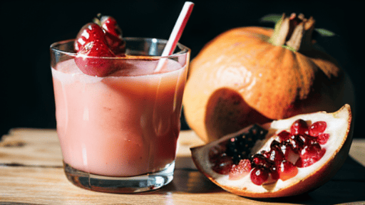 A glass of pomegranate juice with a straw and a slice of pomegranate.