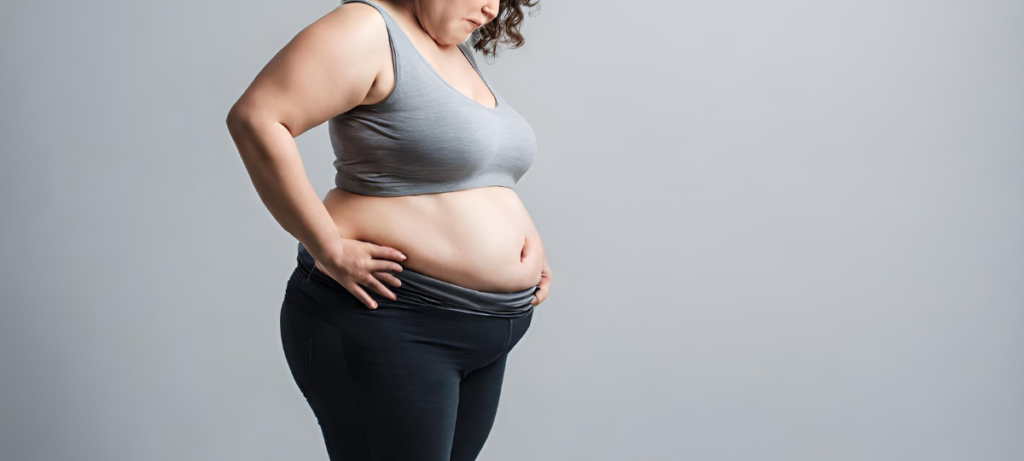 A woman is posing with her hands on her stomach.