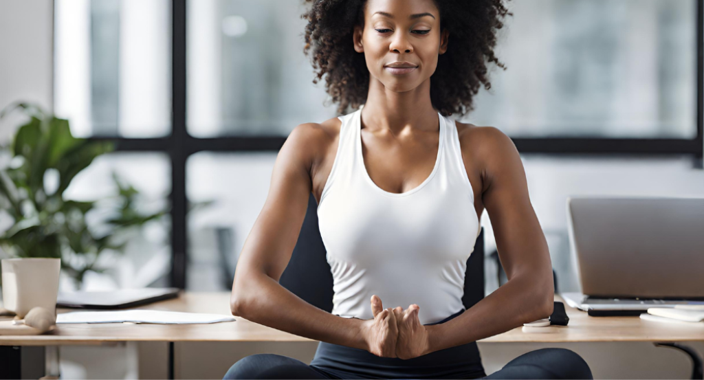 A woman meditating in front of a laptop.